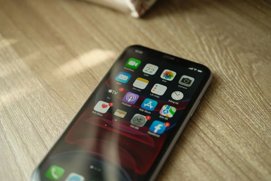 Close-up of hands typing on a laptop beside a cup of coffee on a wooden desk.